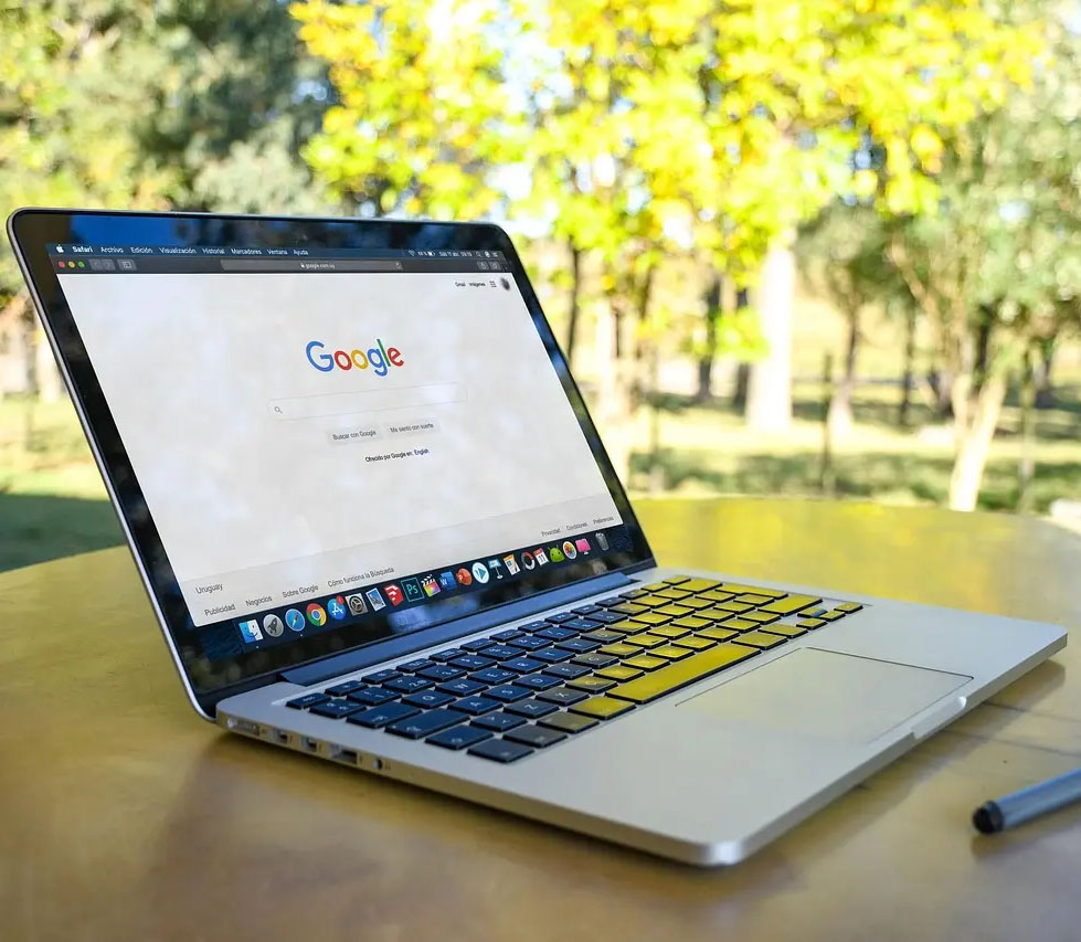 Laptop open on a table with Google search page to search for a Google Business profile with trees in the background.